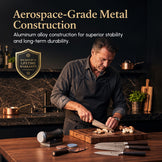 A man in a dark kitchen preparing food on a wooden cutting board, with multiple kitchen knives displayed in the foreground. Text at the top reads 'Aerospace-Grade Metal Construction' and 'Aluminum alloy construction for superior stability and long-term durability.