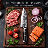 A multipurpose chef knife with a hammered steel blade and black handle is displayed on a dark wooden cutting board, surrounded by raw ingredients including sliced beef, salmon, red onion, tomatoes, parsley, and rosemary. Text at the top reads 'MULTIPURPOSE CHEF KNIFE' and 'Slice.