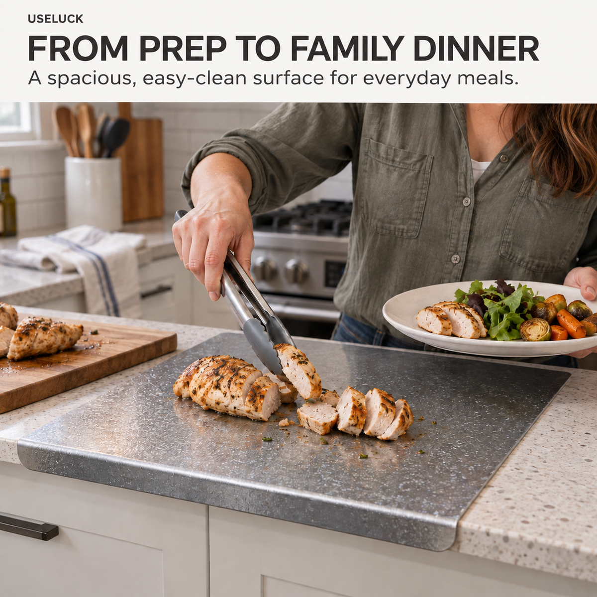 A person in a kitchen uses metal tongs to slice grilled chicken on a rectangular gray cutting board set on a speckled countertop. A plate of salad and roasted vegetables sits nearby, with a text banner at the top reading 'FROM PREP TO FAMILY DINNER' and the brand name USELUCK.
