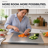 A woman in a kitchen slices carrots on a large gray cutting board, with vegetables and cabinets in the background. Text at the top reads 'USELUCK MORE ROOM.