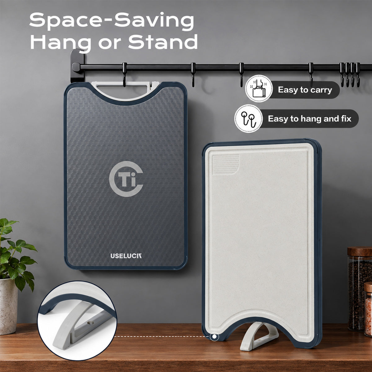 A foldable cutting board shown in two states: hanging on a black wall rack on the left, and folded flat on a wooden table on the right. The product has a dark gray textured front, a white underside, and a navy blue border.