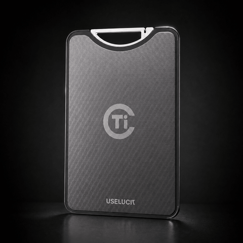 A sleek, rectangular titanium card case with a textured dark gray finish, featuring a silver 'Ti' logo and the brand name 'USELUCI' at the bottom. It is shown standing upright on a dark reflective surface against a black background.