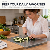A woman in a white shirt slices a zucchini on a gray cutting board in a bright kitchen. Text at the top reads 'USEULUCK PREP YOUR DAILY FAVORITES Odor-resistant titanium for vegetables, fruit and more.